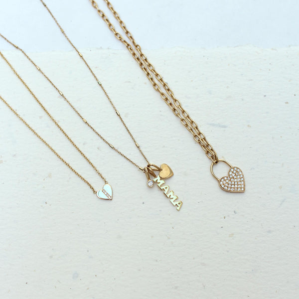a Zoë Chicco 14k Gold Midi Bitty Pavé Diamond Line Heart Necklace laying flat against a speckled background with two other necklaces