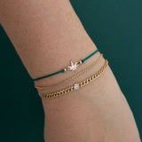 A woman wears the 14k Midi Bitty Mary Jane Cord Bracelet  with a small curb chain with floating diamond