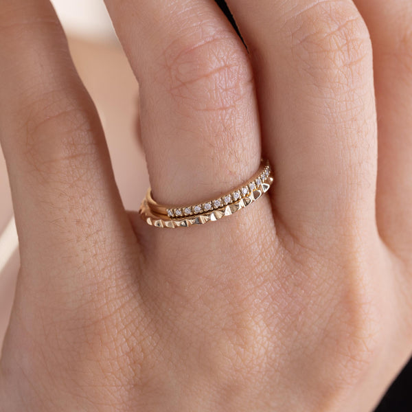 A woman is wearing Zoe Chicco rings including: 14k Tiny Spikes Eternity Ring and 14k Pavé Diamond Half Eternity Band Ring