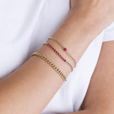 a woman's wrist wearing a Zoë Chicco 14k Gold Emerald Cut Ruby Small Curb Chain Bracelet stacked with a 14k Ruby Tennis Segment Small Curb Chain Bracelet and a 14k Medium Curb Chain Bracelet