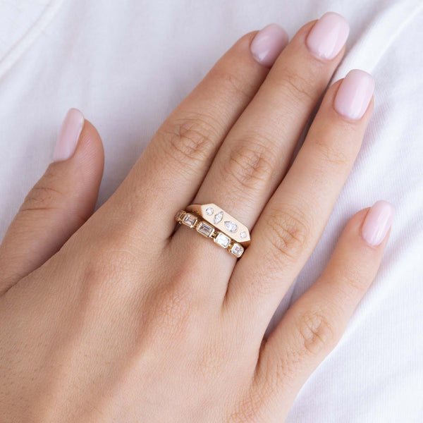 woman's hand wearing a Zoë Chicco 14k Gold 5 Emerald Cut Diamond Bezel Ring stacked with a 14k Diamond Mosaic Brushed Gold Elongated Hexagon Signet Ring on her middle finger