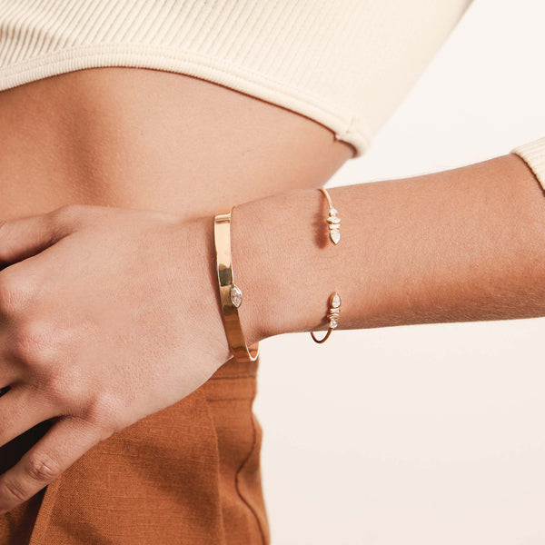 woman resting her hand on her waist wearing a Zoë Chicco 14k Gold Marquise Diamond Flat Wide Cuff Bracelet stacked with a 14k Mixed Fancy Cut Diamond Cuff Bracelet on her wrist