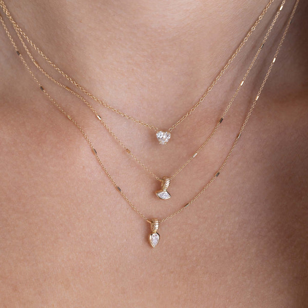 close up of a woman wearing a Zoë Chicco 14k Gold Marquise Diamond Bead Pendant Necklace layered with a 14k Pear Diamond Bead Pendant Necklace and a 14k Prong Heart Shaped Diamond Necklace