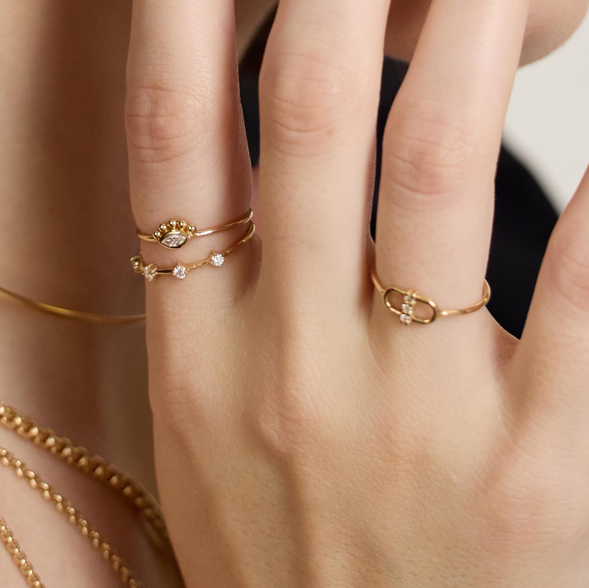 Zoe Chicco 14K gold rings and bracelets on a neutral background