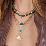 Close-up of layered necklaces with green and gold pendants on a person wearing a brown leather jacket featuring 14k Pear Malachite Pendant Rondelle Bead Necklace with 4 Prong Diamonds