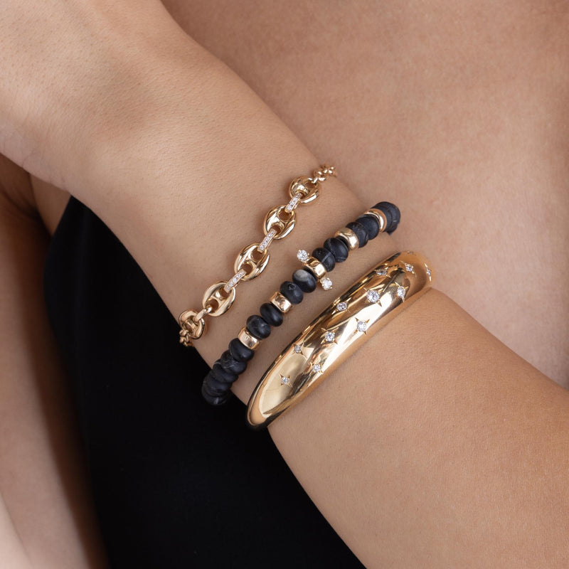 woman's wrist wearing a Zoë Chicco 14k Gold Mixed Small & Large Mariner Chain with Diamond Links Bracelet stacked with a 14k Gold & Matte Black Agate Rondelle Bead Bracelet with 2 Diamonds and a Scattered Diamonds Medium Aura Cuff