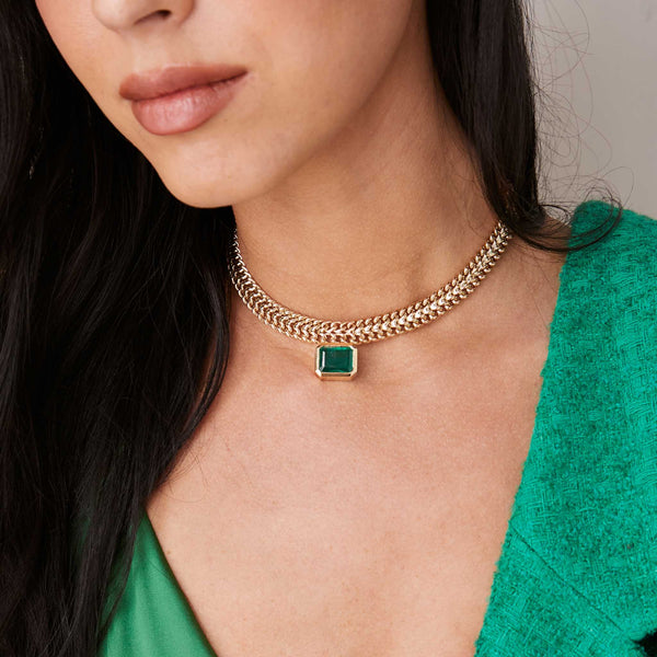 a woman standing against a grey background wearing a Zoë Chicco 14k Gold One of a Kind Emerald Cut Emerald Bezel Double Wide Curb Chain Necklace
