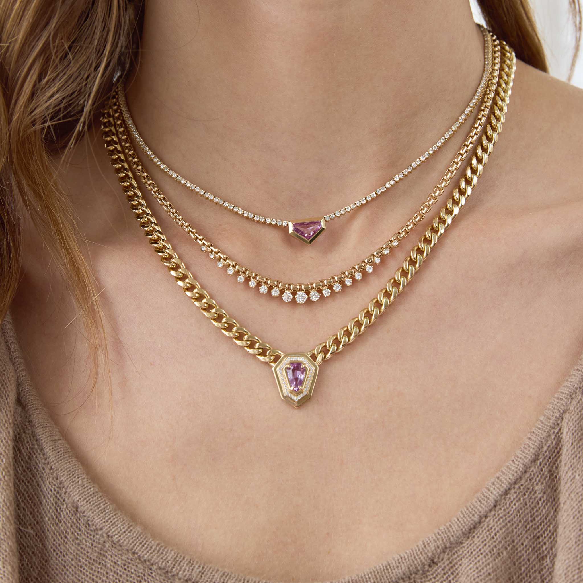 Zoe Chicco 14K Gold Close-up of a person wearing multiple gold necklaces with gemstone pendants.