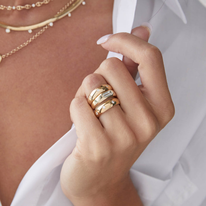 woman in white shirt wearing a Zoë Chicco 14k Gold One of a Kind Baguette Diamond Signet Ring stacked with two half round rings on her ring finger