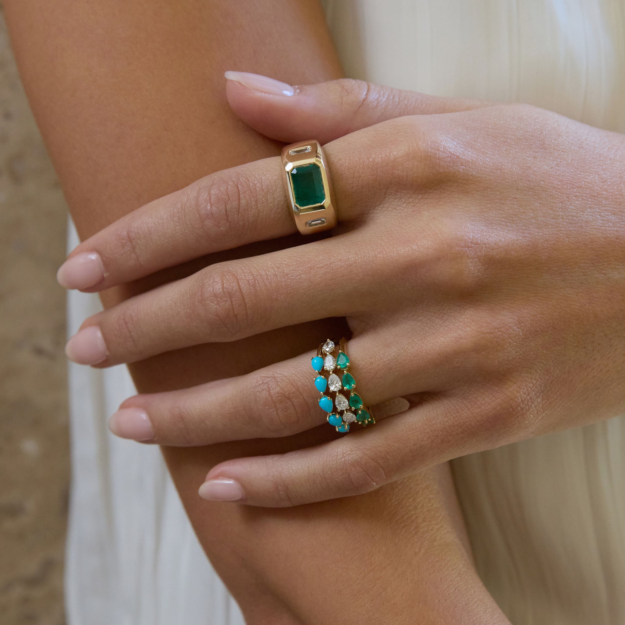 A woman wears the 5 pear band rings in turquoise, diamond and emerald on her ring finger.  And the emerald one of a kind on her pointer.