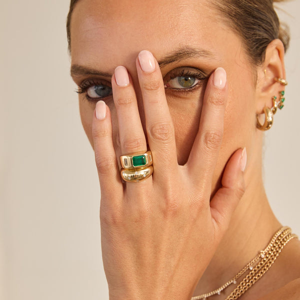 Zoe Chicco 14K gold rings on a womans hand that is partially covering her face. 