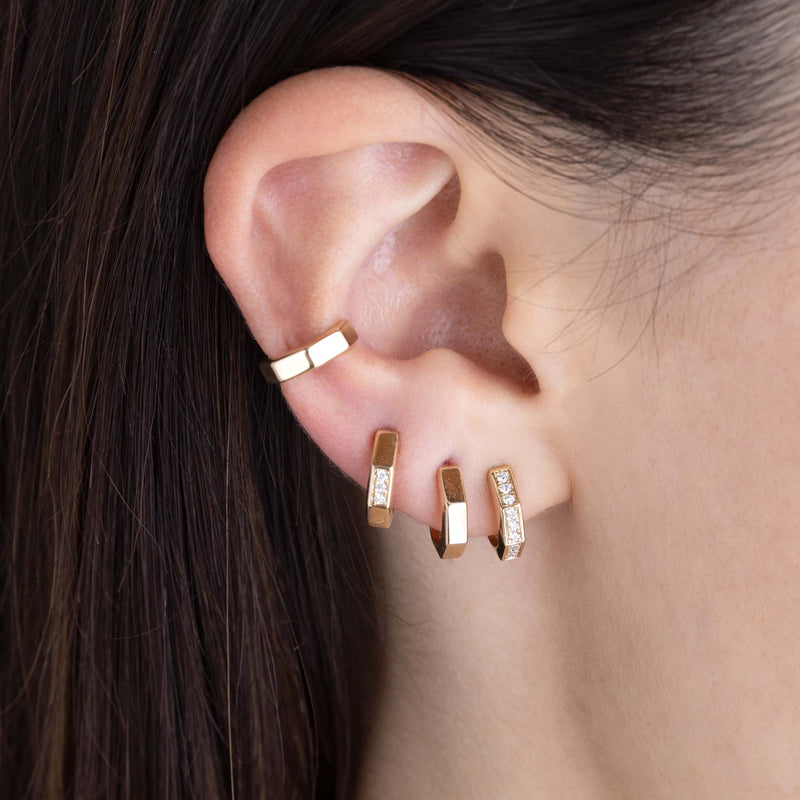 close up of a woman's ear wearing a Zoë Chicco 14k Gold Octagon Huggie Hoop Earring and two Pavé Diamond Octagon Huggie Hoops on her ear along with a 14k Gold Octagon Ear Cuff