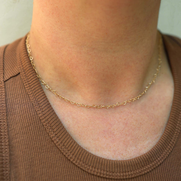 A woman in a brown shirt is wearing Zoe Chicco's 14k Gold Heart Link Necklace.