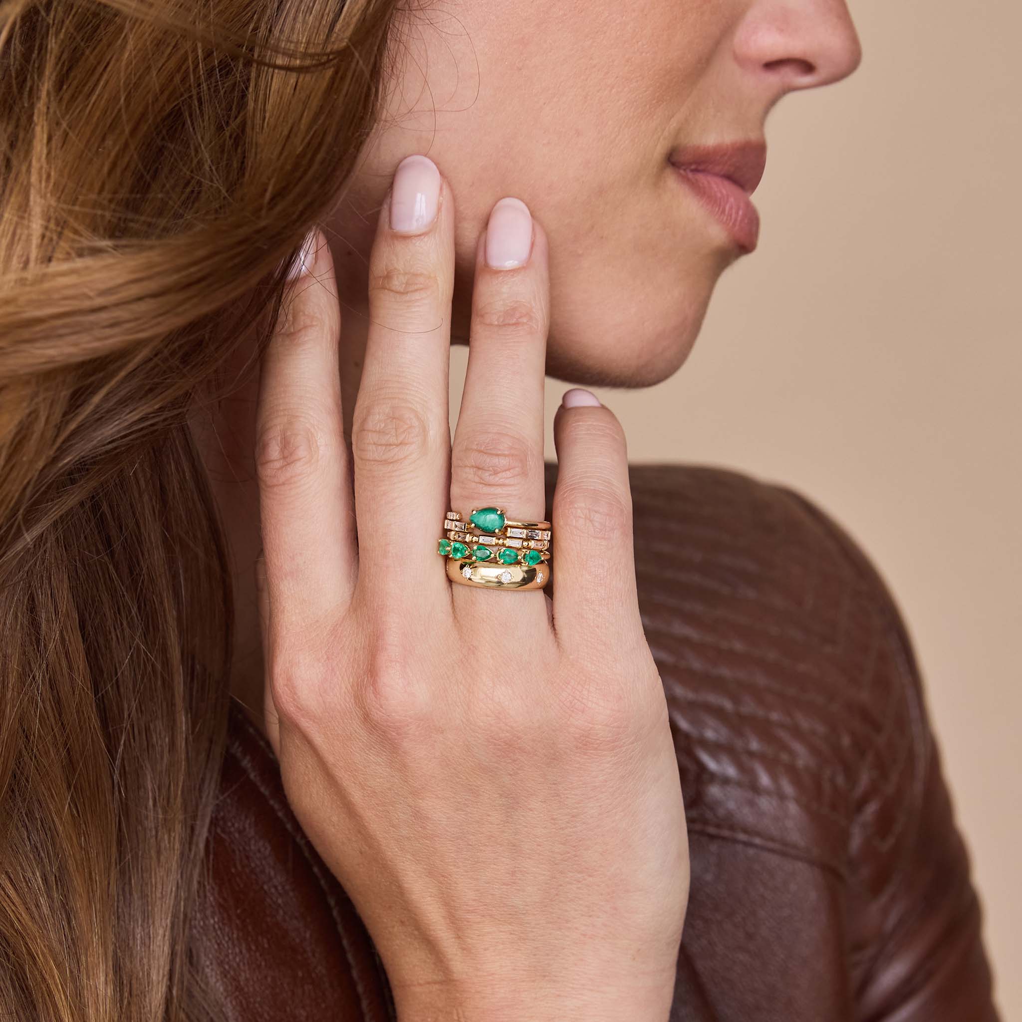 Close-up of a hand wearing gold rings with 14k Pear Malachite & Pavé Diamond Open Ring against a neutral background