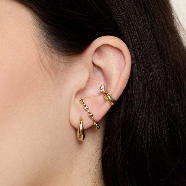 close up of a woman's ear wearing a Zoë Chicco 14k Gold Small Mariner Chain Lobe Cuff Stud Earring in her second piercing layered with a Tapered Dome Hoop Earring and a 14k Marquise Diamond Chubby Ear Cuff
