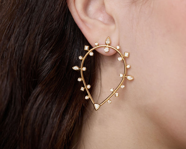 Close up of a Zoe Chicco 14k gold hoop earring with small diamonds worn by a person