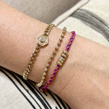 close up of a woman's wrist wearing a Zoë Chicco 14k 5mm Gold & Diamond Rondelle Bead Paracord Bracelet in Pink Purple stacked with a Prong Diamond Dash Tennis Bracelet and a Diamond Hexagon Halo Curb Chain Bracelet