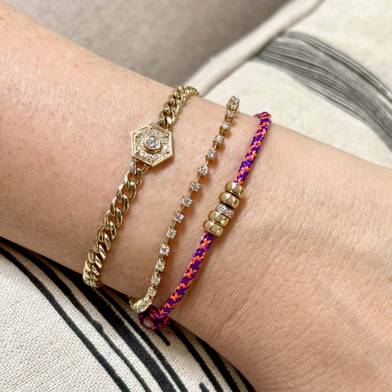 close up of a woman's wrist wearing a Zoë Chicco 14k 5mm Gold & Diamond Rondelle Bead Paracord Bracelet in Pink Purple stacked with a Prong Diamond Dash Tennis Bracelet and a Diamond Hexagon Halo Curb Chain Bracelet