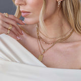 woman in an off shoulder top wearing a Zoë Chicco 14k Gold 15 Graduated Prong Diamond Linked Bar Necklace layered with a Diamond Tennis Necklace, 14k Pear Diamond Bezel Pendant Snake Chain Necklace, and a Large Scattered Star Set Diamond Dog Tag Pendant on a 14k Gold Extra Small Box Chain Necklace