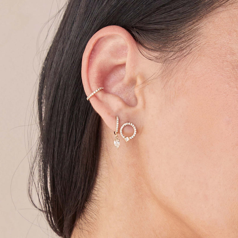 woman's ear wearing a Zoë Chicco 14k Gold Princess Diamond & Diamond Circle Stud Earring layered with a Pear Diamond Pave Diamond Hinge Huggie Hoop