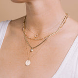 woman in a white tank top wearing a Zoë Chicco 14k Gold Princess Diamond & Diamond Circle Necklace layered with a 14k Linked Prong Diamond & Medium Paperclip Rolo Chain Necklace, 14k Pear Diamond Bezel Pendant Snake Chain Necklace, and a 14k Small Mantra Diamond Border Necklace on Tiny Bar & Cable Chain engraved with "Never give up"