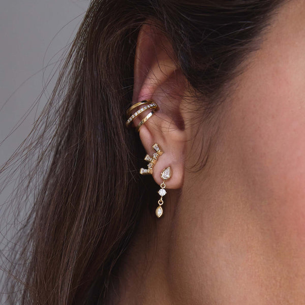 woman's ear wearing a Single Zoë Chicco 14k Gold Tapered Baguette & Prong Diamond Curve Stud Earring in her second piercing layered with a Mixed Cut Diamond Drop Earring