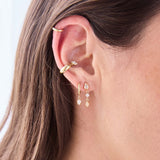 close up of a woman's ear wearing a Zoë Chicco 14k Gold Linked Mixed Diamond Drop Earring layered with a 14k Dangling Pear Diamond Small Hinge Huggie Hoop and a Marquise Diamond Chubby Ear Cuff