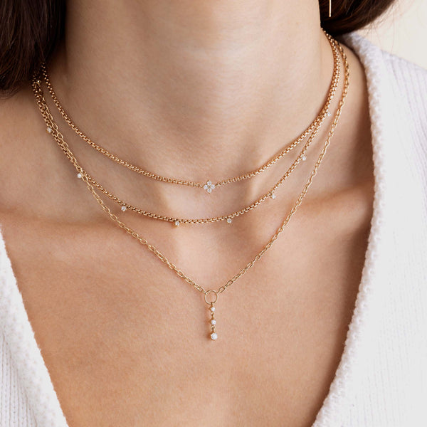 A woman is wearing Zoe Chicco's 14k Prong Diamond Quad Box Chain Necklace, 14k 9 Prong Diamond Small Box Chain Necklace and 14k Circle Square Oval Chain Lariat with Graduated Prong Diamond Drop.