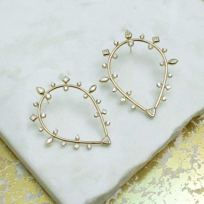 14k Mixed Diamond Upside Down Teardrop Earrings laying on a white marble background