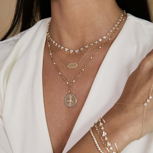 woman in an ivory blouse wearing a Zoë Chicco 14k Gold Linked Prong Diamond & Medium Paperclip Rolo Chain Necklace with a Bee Sunbeam Medallion Clip on Charm Pendant clipped onto the center of the necklace