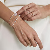 woman holding her hands out in front wearing a Zoë Chicco 14k Gold Diamond Bezel Tennis Segment Curb Chain Bracelet layered with various other bracelets and a hand chain