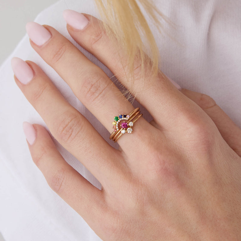 close up of a woman's hand wearing a Zoë Chicco 14k Gold Graduated Prong Rainbow Sapphire & Pavé Diamond Double Arch Ring stacked with a Prong Ruby Ring and a 14k 3 Graduated Prong Diamond Curve Ring on her middle finger