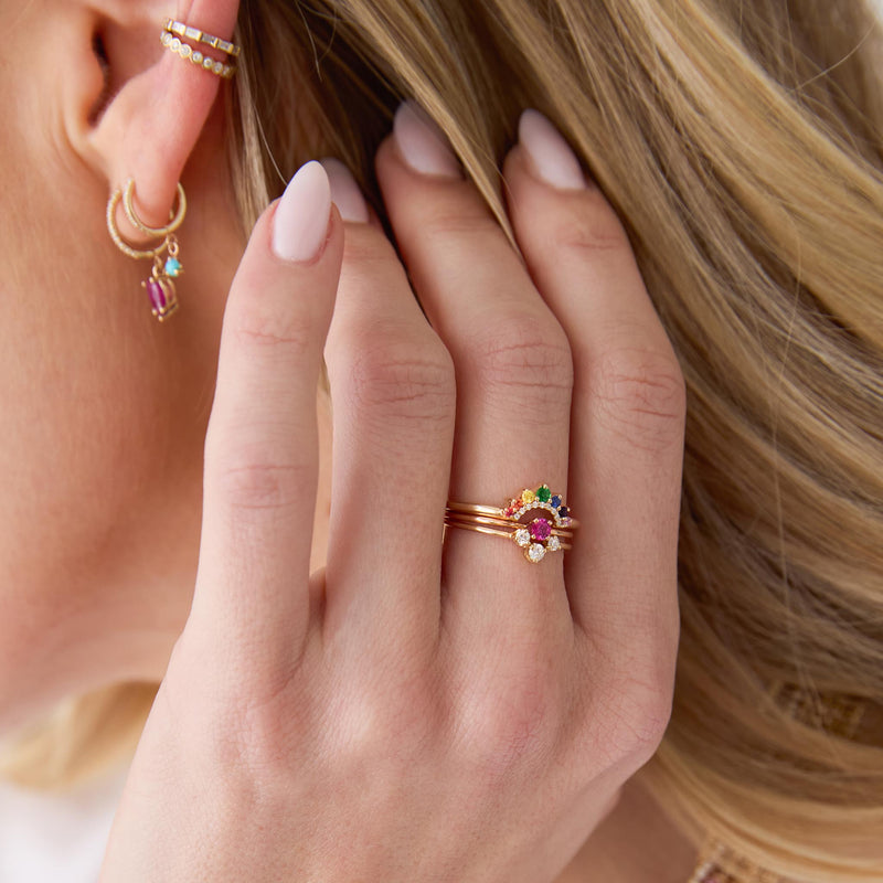 woman with her hand raised to her neck wearing a Zoë Chicco 14k Gold Graduated Prong Rainbow Sapphire & Pavé Diamond Double Arch Ring stacked with a Prong Ruby Ring and a 14k 3 Graduated Prong Diamond Curve Ring on her middle finger