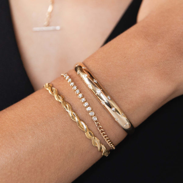A Zoe Chicco stack includes a small aura cuff with starset diamonds, a bezel diamond tennis bracelet with small curb chain and a twisted snake chain bracelet.