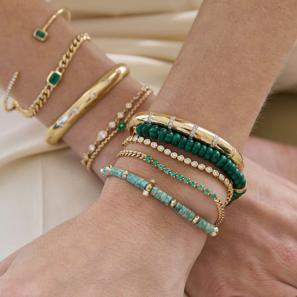 A woman wears exclusive turquoise bracelet with prong diamonds and a mix of emerald and malachite styles with diamonds.