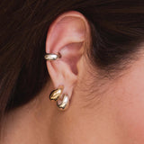 close of a woman's ear wearing a Zoë Chicco Sterling Silver Small Aura Huggie Hoop Earring layered with a 14k Gold Small Aura Huggie Hoop in her second percing and a Sterling Silver Wide Chubby Ear Cuff