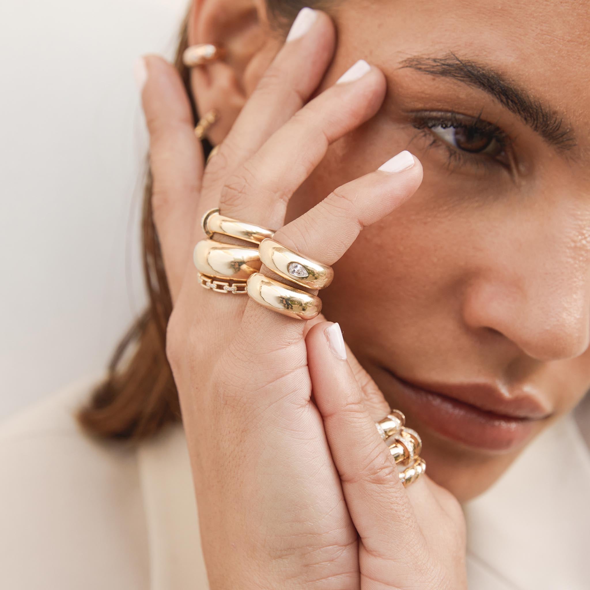 woman holding her hand up to her face wearing a Zoë Chicco 14k Yellow Gold Pear Diamond Small Aura Ring stacked with a 14k Gold Small Aura Ring on her pinky finger