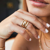 Woman's hand resting under her chin wearing a Zoë Chicco 14k Gold 10 French Set Diamond Half Round Ring stacked with a Baguette Diamond Eternity Ring and a Round Diamond Small Aura Ring stacked together on her ring finger