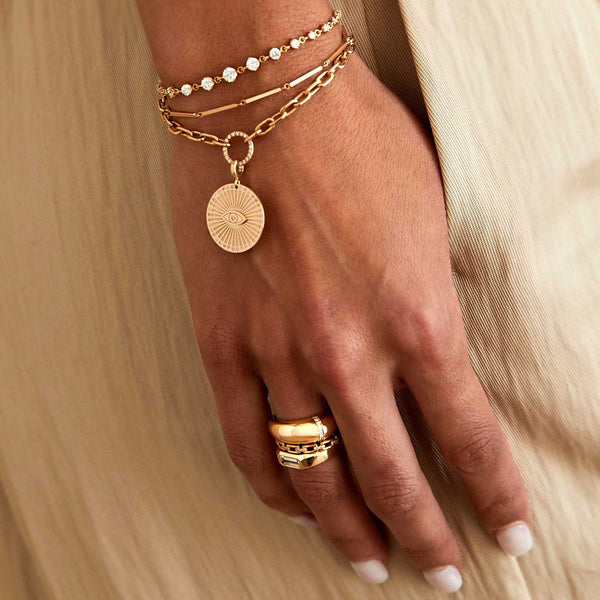 woman's hand with her thumb in her pocket wearing a Zoë Chicco 14k Gold Linked Bar Bracelet layered with two other bracelets on her wrist