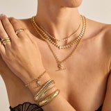 Layers on Zoe Chicco 14k gold and diamond necklaces, bracelets and rings worn by a woman on a neutral background