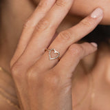 close up of a woman's hand resting against her chin wearing a Zoë Chicco 14k Gold Small Diamond Bezel Heart Ring on her ring finger