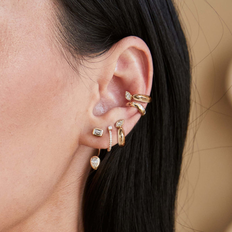 close up of a woman's ear wearing a Zoë Chicco 14k Gold Marquise Diamond Chubby Ear Cuff layered with another ear cuff and three earrings