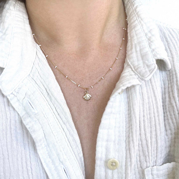 close up of a woman in a white buttoned shirt wearing a Zoë Chicco 14k Gold and Diamond Seashell White Enamel Satellite Chain Necklace