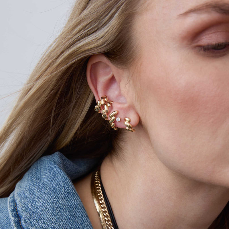 woman's ear wearing a Zoë Chicco 14k Gold San Marco Half Hoop Earring layered with a diamond stud, San Marco Chain Lobe Earring, and 2 San Marco Chain Ear Cuffs
