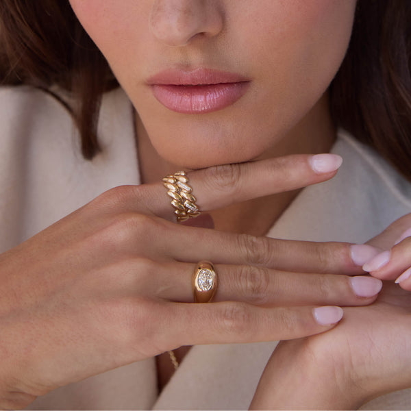 woman with her hand resting under her chin wearing a Zoë Chicco 14k Gold San Marco Band Ring on her index finger and a one of a kind Oval Diamond Signet Ring on her ring finger