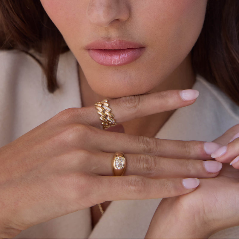 woman with her hand resting under her chin wearing a Zoë Chicco 14k Gold San Marco Band Ring on her index finger and a one of a kind Oval Diamond Signet Ring on her ring finger