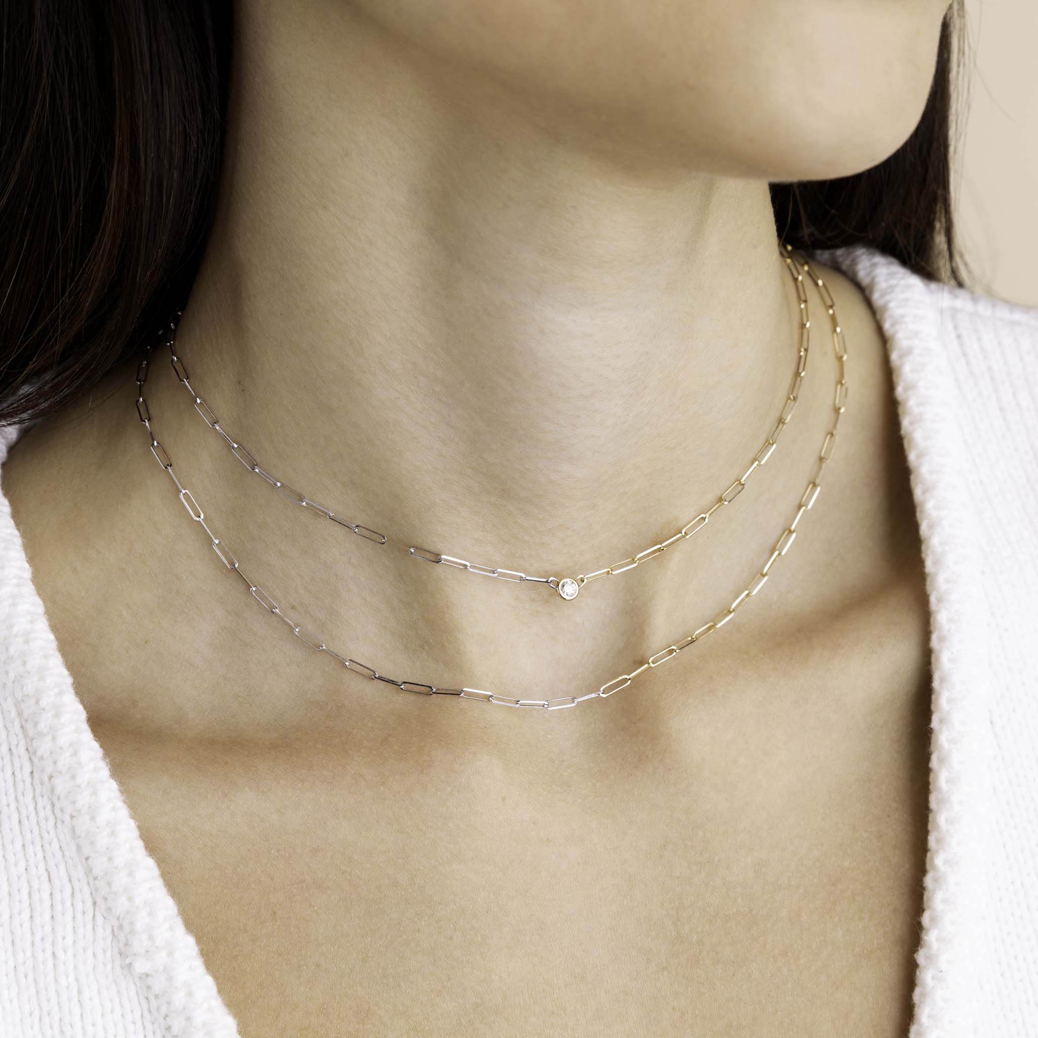 A model with dark hair is wearing Zoe Chicco's 14k Two Tone Gold Small Paperclip Chain Necklace and 14k Floating Diamond Two Tone Gold Small Paperclip Chain Necklace.