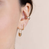 A woman with dark hair is wearing Zoe Chicco's 14k Gold Safety Pin Threader Earring, 14k Pavé Diamond Thick Small Oval Hinge Huggie Hoops and  double ear cuff