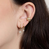 Zoe Chicco 14K  Close-up of a person wearing gold hoop earrings with diamonds