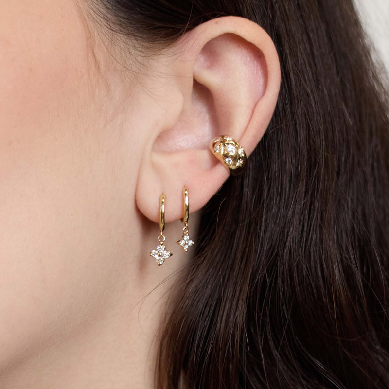 Zoe Chicco 14K  Close-up of a person wearing gold hoop earrings with diamonds